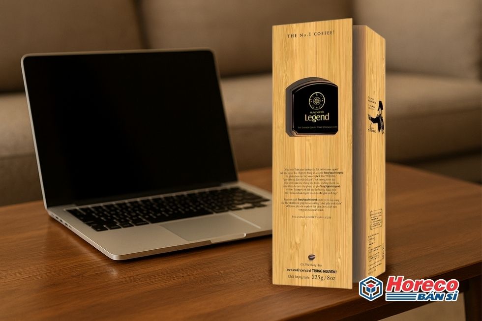 Hàng Tiêu Dùng HORECO https://horeco.vn Gói cà phê LEGEND cạnh máy tính, thể hiện sự kết nối giữa công việc và niềm đam mê cà phê.